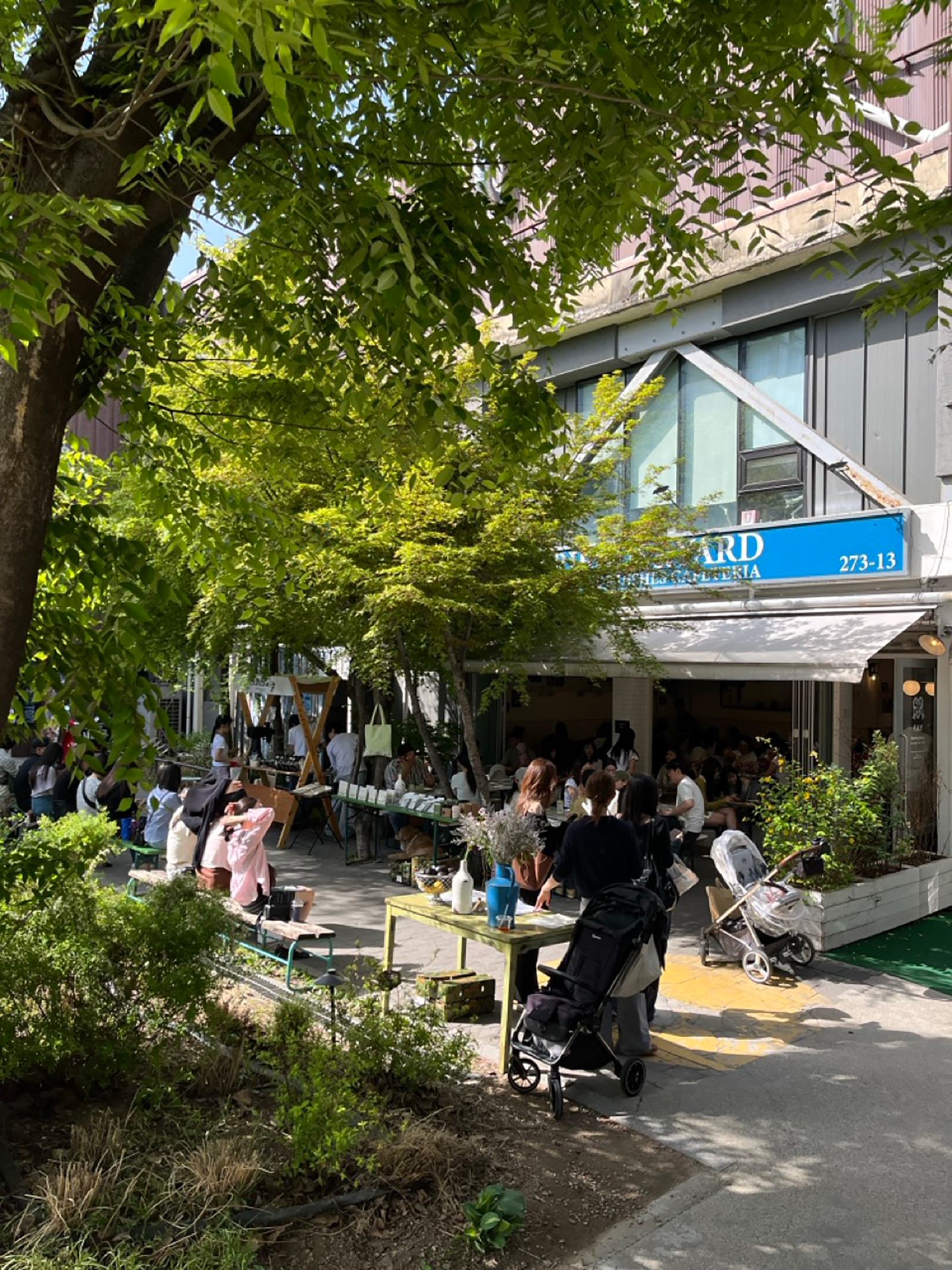 緑に囲まれたFriends & Yardの店先。屋外の席でくつろぐ人々