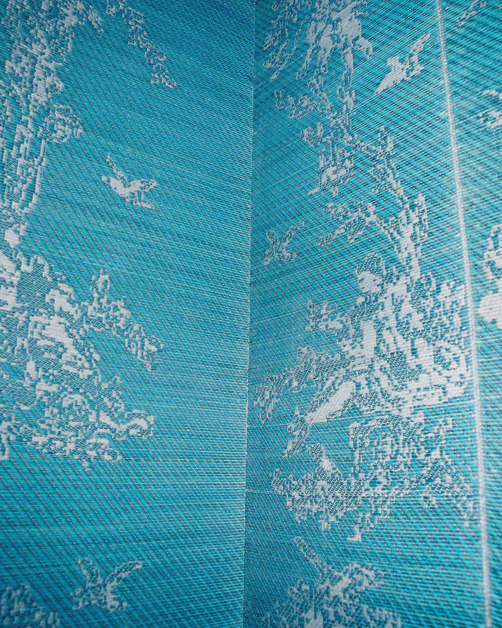Close-up of blue denim fabric with diagonal weave and a pale floral pattern