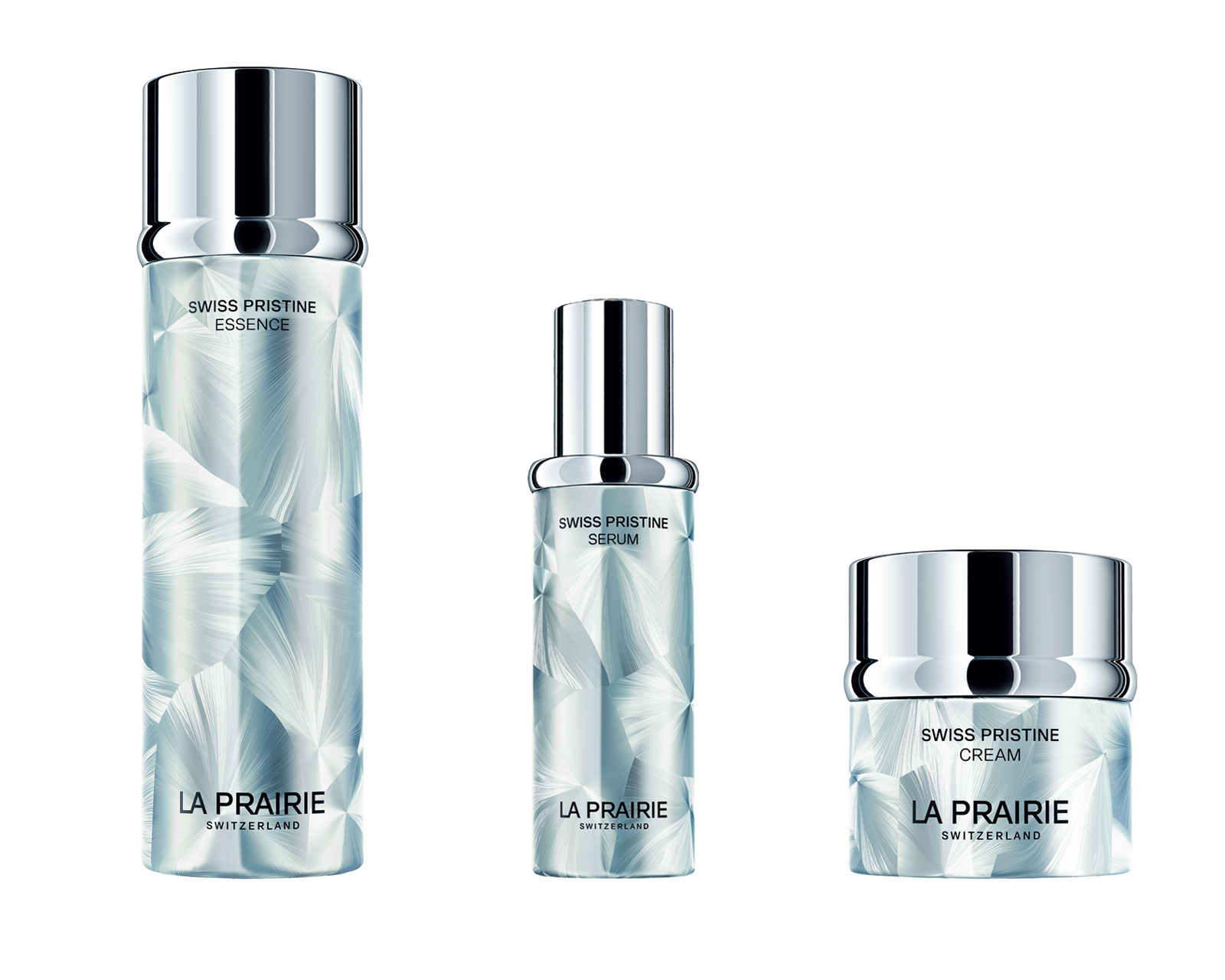 Three La Prairie Swiss Pristine skincare bottles (Essence, Serum, Cream) with icy blue pattern and chrome caps on a white background.