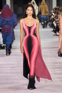 Model walks the runway in a pink and black metallic gradient gown with thin straps and an asymmetric hem.