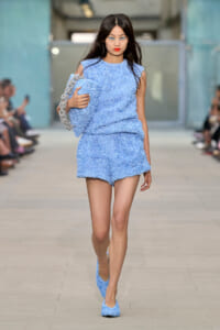 Model walking a runway in a light blue textured matching set and shoes.