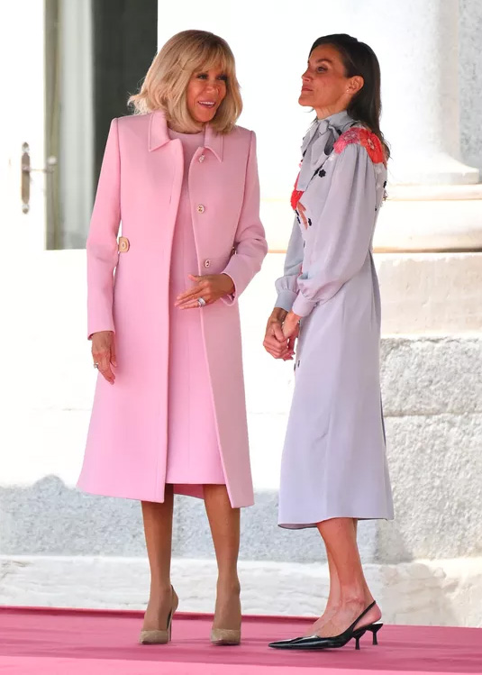 261001-brigitte-macron-letizia-05 | madameFIGARO.jp(フィガロジャポン) 王宮前に並んで立つパウダーピンクのコートのブリジット・マクロン夫人とライトブルーのドレスのレティシア王妃
