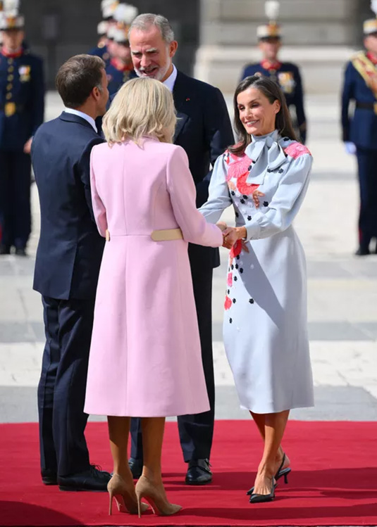 261001-brigitte-macron-letizia-09 | madameFIGARO.jp(フィガロジャポン) パウダーピンクのコート姿のブリジット・マクロン夫人と、花柄のライトブルーのドレスを着たレティシア王妃が握手する様子